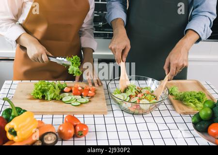 Asiatisches Paar genießt Kochen Gemüsesalat in der Küche. Stockfoto