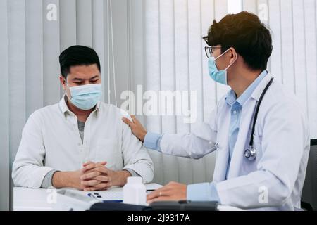 Der Arzt nahm sich Trost im Arm des Patienten, um die Krankheit zu erklären. Stockfoto