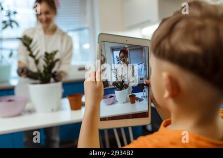 Glückliche Bloggerin nimmt Bestellungen online entgegen und zeigt dem Kunden via Video-Link Blumen. Kleinunternehmen, Online-Bestellungen, Online-Geschäft. Gartenarbeit im Haus Stockfoto