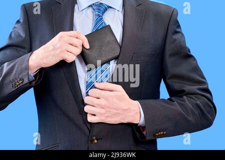 Ein junger Geschäftsmann in einem blauen Hemd und Krawatte verbirgt die Brieftasche eines Mannes in der Innentasche seiner Jacke Stockfoto