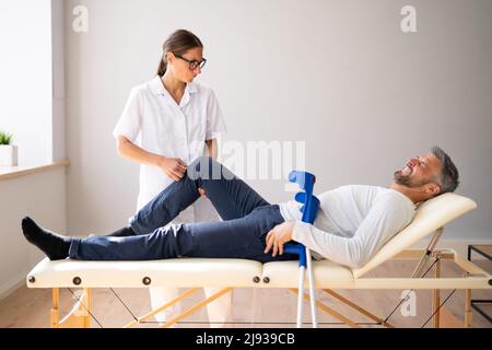 Physiotherapeut Überprüft Das Knie Des Patienten. Physiotherapie Und Schmerzen Stockfoto