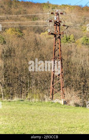Alte rostige Stromversorgung. Hochspannungsleitung. Strommast und Drähte auf einem Himmelshintergrund. Rostiger Eisenmast mit elektrischen Drähten Stockfoto