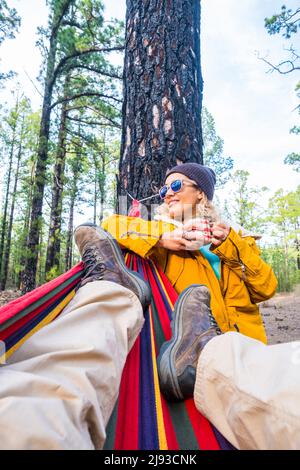 Reisen in der Natur Menschen Konzept Lifestyle - schönes Porträt der jungen erwachsenen Frau aus der Sicht der Beine Blick auf den Mann auf einer Hängematte - f Stockfoto