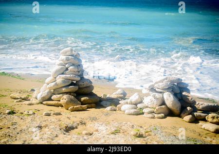 Steinhaufen am Strand auf dem Leuchtturm Phare Des Baleines auf der Insel Ile de Ré in Frankreich an einem sonnigen Sommertag Stockfoto