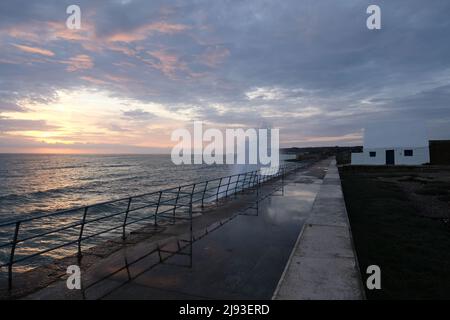 Große Wellen sprühen beim Sonnenuntergang durch das White House Le Don Hilton St Ouens Bay Five Mile Road Jersey Channel Islands auf die Meereswand Stockfoto