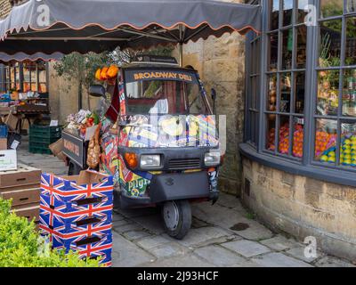 Frontfront des Broadway Deli, in der Cotswolds-Stadt Broadway, Worcestershre, Großbritannien; mit Union Jack-Boxen und Lieferwagen. Stockfoto