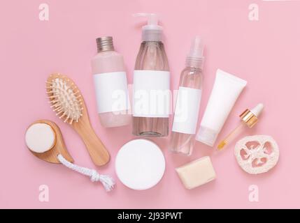 Hausgemachte Bio-Kosmetik in Röhren und Flaschen und umweltfreundliche Accessoires auf rosa Flachlegen, Kopierraum. Draufsicht auf natürliche Schönheitsprodukte für hai Stockfoto