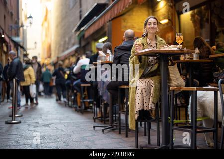 Frau, die auf einer überfüllten Straße in der Bar oder im Restaurant im Freien sitzt Stockfoto