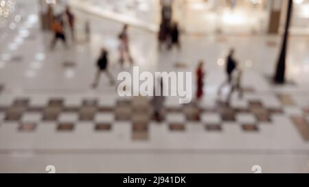 Verschwommenes Bild von Menschen, die in der Halle des Einkaufszentrums gehen. Hintergrundbild. Stockfoto