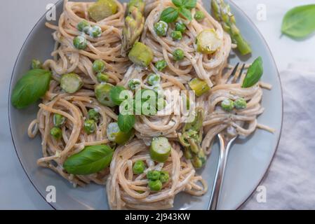 italienische Spaghetti mit grünem Spargel auf einem Tisch Stockfoto