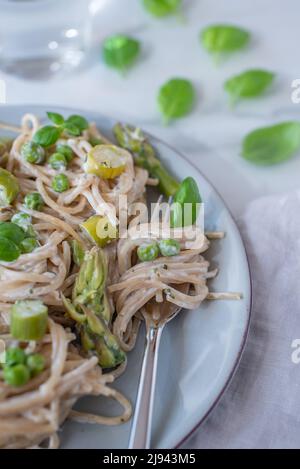 italienische Spaghetti mit grünem Spargel auf einem Tisch Stockfoto