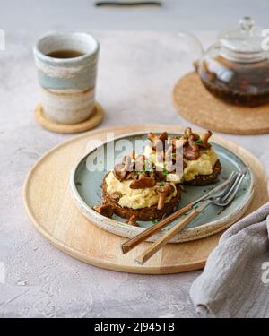 Gemütliches Frühstück mit Rührei mit Pfifferlinge auf Brötchen mit Tee, Kopierplatz Stockfoto