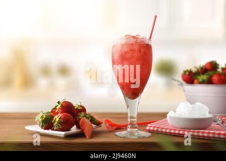 Obst-Granita mit reifen Früchten auf einem Teller und zerdrücktes Eis in einer Schüssel auf einem Holztisch in einer Küche. Vorderansicht. Horizontale Zusammensetzung. Stockfoto