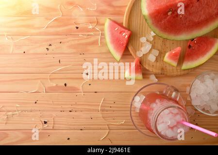Glas mit natürlicher Wassermelone Getränk mit Eis auf einem Holztisch mit Früchten um. Draufsicht. Horizontale Zusammensetzung. Stockfoto