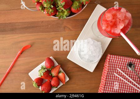 Erdbeer-Granita auf Holztisch mit reifen Früchten. Draufsicht. Horizontale Zusammensetzung. Stockfoto