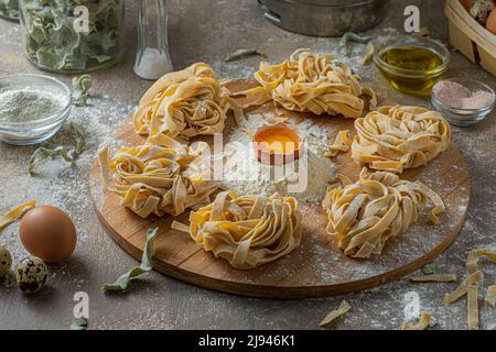 Frisch zubereitete Tagliatelle-Pasta mit Eiern und Mehl auf Holzbrett Stockfoto