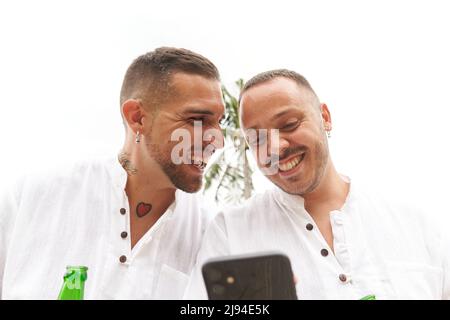 Schwule Paare lachen zusammen, während sie das Mobiltelefon im Freien benutzen Stockfoto