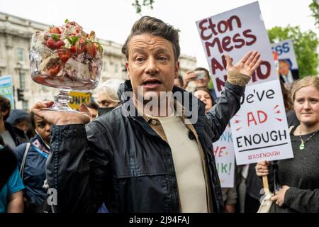 London, Großbritannien. 20 Mai 2022. Fernsehkoch Jamie Oliver vor der Downing Street bei einem Protest in Eton Mess. Um die Gesundheit von Kindern zu schützen, wollen die Demonstranten, dass die Regierung ihre Entscheidung, ein Jahr lang ein Verbot von „Buy-one-get-one-free“-Geschäften für ungesunde Lebensmittel und ein Verbot von TV-Junk-Food-Anzeigen vor einer Wendeschneidbildung im Jahr 9pm zu verschieben, rückgängig macht. Die Regierung sagt, dass die Verschiebung eine Überprüfung der Auswirkungen auf die Haushalte angesichts der Lebenshaltungskrise ermöglichen wird. Eton Mess ist ein Dessert, das darauf verweist, wo Boris Johnson, Premierminister, zur Schule ging. Kredit: Stephen Chung / Alamy Live Nachrichten Stockfoto