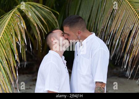 Gay paar in weißen T-Shirt küssen neben einer Palme Stockfoto