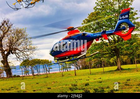 Blau und rot G-GLAB - Airbus Helicopter H135 schwebt in Vorbereitung auf den Start, Applecross Peninsula, Bealach na Ba, North Coast 500, Schottland Stockfoto