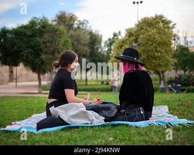 Horizontale Vollansicht von zwei Frauen, die auf einer Picknickdecke im Park sitzen Stockfoto