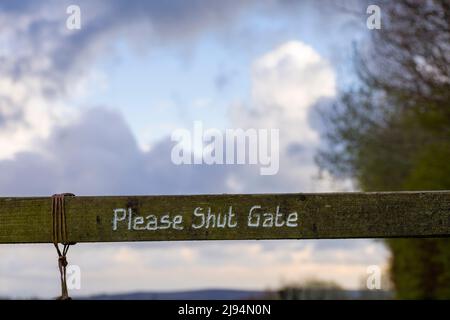 Please Shut Gate bemalt auf ein Holztor auf dem Coleridge Way Fußweg zwischen Wheddon Cross und Lype Hill in den Brendon Hills, Exmoor National Park, Somerset, England. Stockfoto