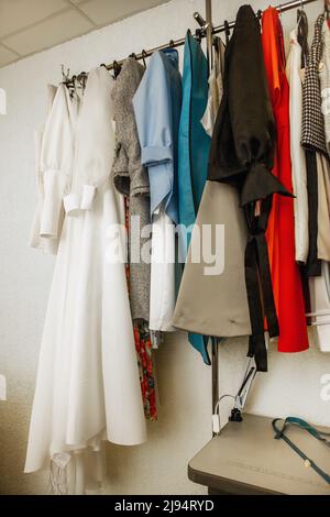 Verschiedene Kleider hängen an der Schiene im Dachatelist. Handgemachte Frauenkleidung, Slow Fashion Stockfoto