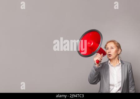 Reife Frau, die über Megaphon schreit Stockfoto
