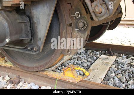 Der Eisenbahnwaggon ist gegen Wegrollen mit einem Unterlegkeil gesichert Stockfoto