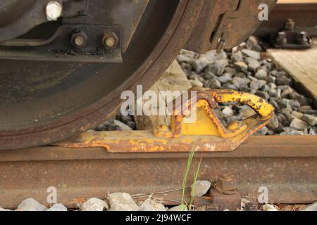 Der Eisenbahnwaggon ist gegen Wegrollen mit einem Unterlegkeil gesichert Stockfoto