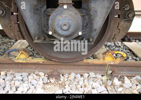 Der Eisenbahnwaggon ist gegen Wegrollen mit einem Unterlegkeil gesichert Stockfoto