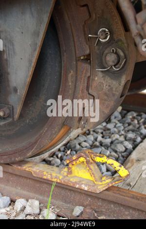 Der Eisenbahnwaggon ist gegen Wegrollen mit einem Unterlegkeil gesichert Stockfoto