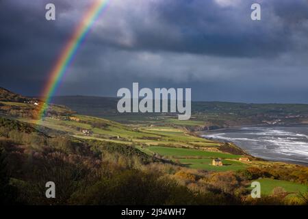 Stürmisches Wetter und ein Regenbogen über Robin Hood's Bay aus Ravenscar, North Yorkshire, England, Großbritannien Stockfoto