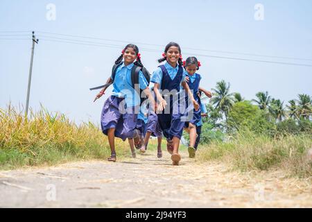 Gruppe von Schulmädchen, die im Rennen nach der Schule in der Nähe von Bauernland im Dorf nach Hause laufen - Konzept der aufgeregt, fröhlich und energisch Stockfoto