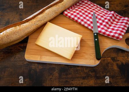 Käsescheibe auf einem Holzbrett mit Baguette Stockfoto