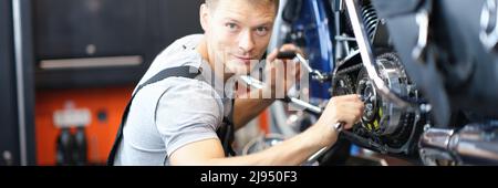 Männlicher Mechaniker in einer Garage, der ein Motorrad repariert Stockfoto