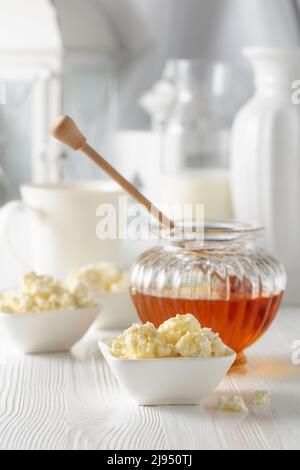 Frisch hausgemachter Hüttenkäse oder Ricotta mit Honig auf einem weißen Holztisch. Stockfoto