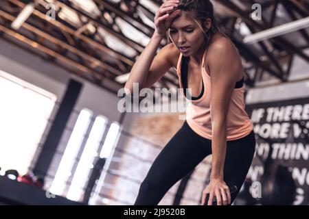 Blick aus der unteren Perspektive auf die müden kaukasischen jungen Boxerinnen, die im Fitnessclub stehen Stockfoto
