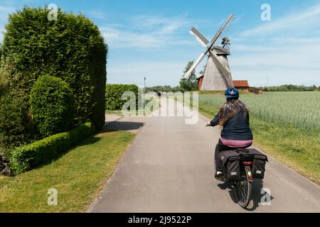 Frau auf einem E-Bike, die in Richtung der Schuttenfabrik aus dem Jahr 1802 in Petershagen-Bierde fährt Stockfoto