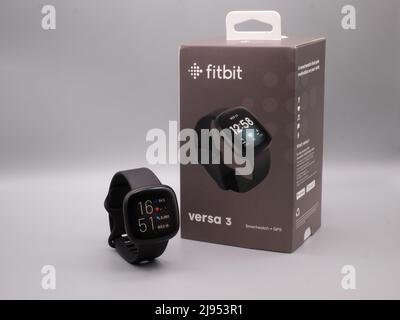 Mai 2022, UK: Fitbit Versa 3 schwarzer Fitness Tracker auf weißem Hintergrund mit Einzelhandelsverpackung und eingeschaltetem fitbit neben der Box Stockfoto