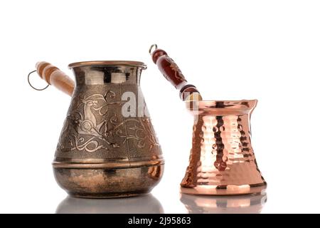 Zwei türkische Cezve-Kaffeekannen aus Kupfer mit Holzgriff, Nahaufnahme, isoliert auf weißem Hintergrund. Stockfoto