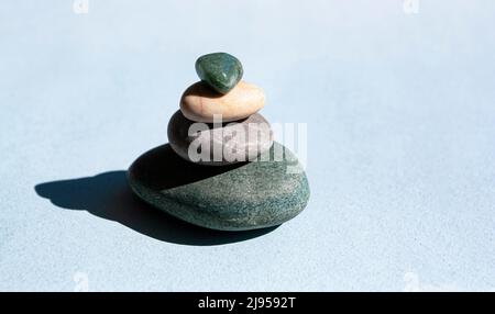 Steinberg auf blauem Hintergrund, ein Turm aus vier Steinen, einfache ausgewogene Steine, Einfachheit, Harmonie und Balance. Minimalistisches Konzept. Stockfoto