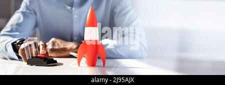 Der Geschäftsmann Hand mit Raketen durch Drücken der roten Taste Stockfoto