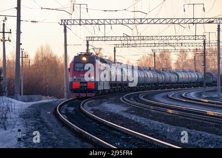 SHARYA, RUSSLAND - 19. MÄRZ 2022: Russische moderne Elektrolokomotive 2ES5K 'Ermak' mit Güterzug in der Abendlandschaft. Russische Eisenbahn Stockfoto