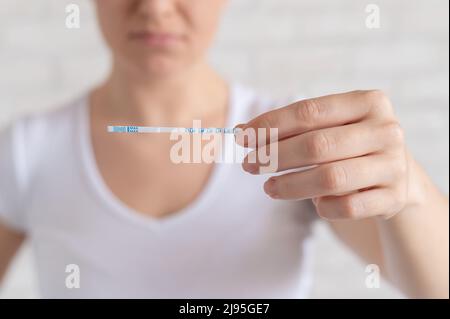 Unglückliche Frau zeigt einen schnellen negativen Test auf Eisprung. Das Konzept der Verletzung der weiblichen Fortpflanzungsfunktion. Frustriertes Mädchen. Luteinisierend Stockfoto