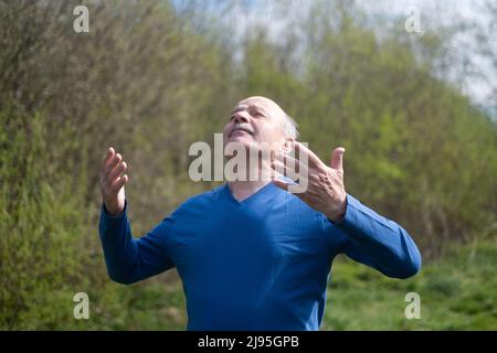Senior Läuferin mit Armband beim Stretching, beim Atmen frischer Luft. Frühling Natur. Gesunde Lebensweise im Alter. Stockfoto