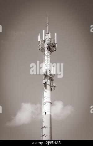 Altes Schwarz-Weiß-Bild Rotweißer 5G Turm mit blauer Himmel Hintergrundstrahlung tötet uns in Playa del Carmen in Mexiko. Stockfoto