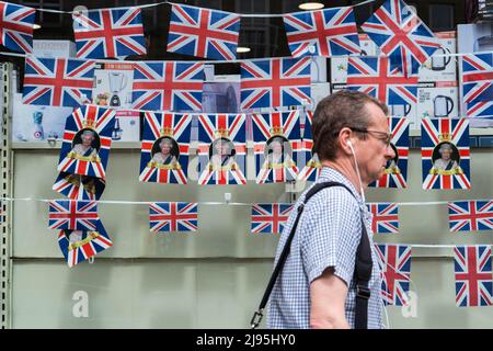 London, 20. Mai 2022. . Ein Fußgänger geht vor dem Platinum Jubilee in Wimbledon, im Südwesten Londons, an der Union Jack-Verblemung vorbei, um die 70-jährige Dienstzeit von Königin Elizabeth II. Als die am längsten dienende britische Monarchin zu würdigen. Das Platinum Jubilee Central Weekend findet vom 2.. Bis 5.. Juni mit Veranstaltungen in ganz Großbritannien statt. Credit. amer ghazzal/Alamy Live News Stockfoto