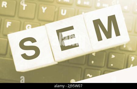 SEM Search Engine Marketing auf einem hölzernen Würfel geschrieben, der auf Computertastatur gesetzt wird. Optimierung Online Business Technologie Konzept Stockfoto
