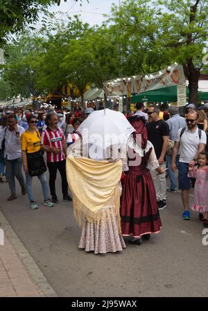 Madrid, Spanien; 15.. Mai 2022: Eine Gruppe von Leuten besucht die Stände auf der Messe Saint Isidro. 2 Frauen mit dem Rücken bekleidet im traditionellen M Stockfoto